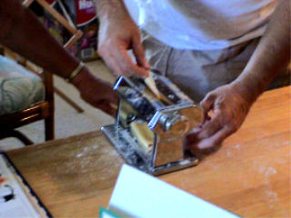 Albert Grande rolls out pasta with a pasta machine.